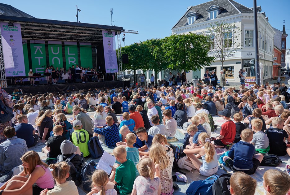 Skoleelever der sidder foran en scene og synger. Foto Jørgen Tveen